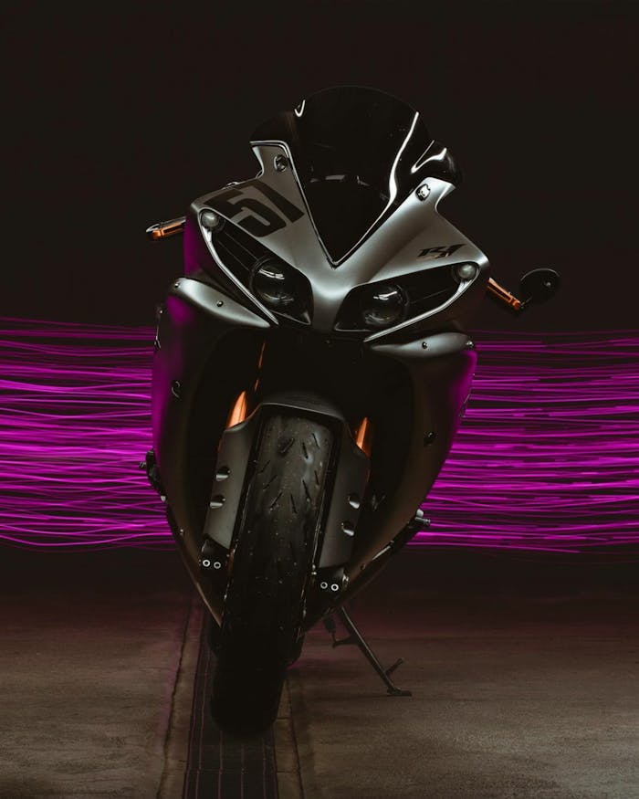 Front view of a sports motorcycle with neon purple streaks behind it.